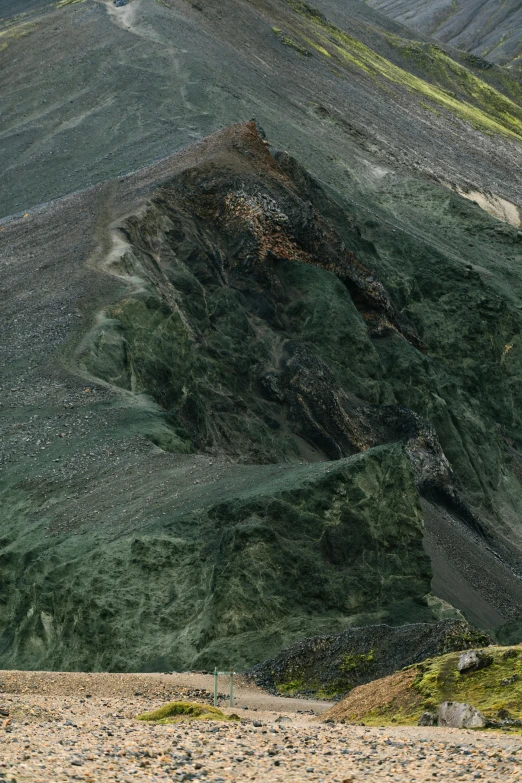 a man riding a horse down a dirt road, looking down at a massive crater, black and green scheme, zoomed out to show entire image, extremely detailed rocky crag