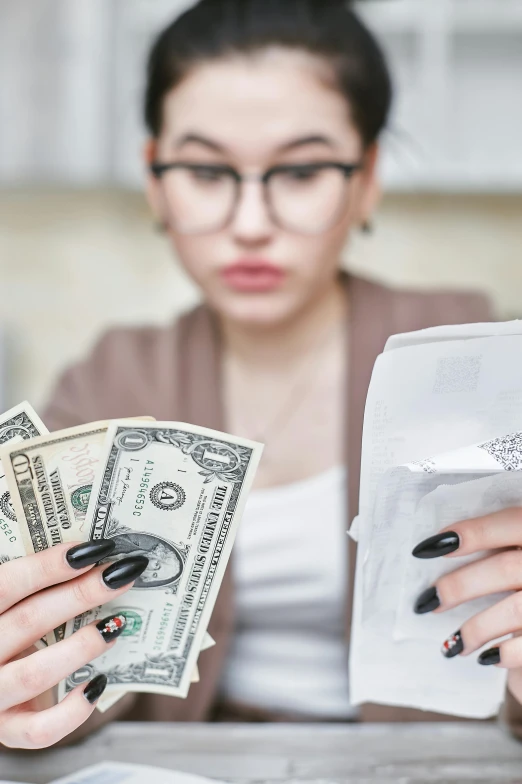 a woman sitting at a table with money in her hands, an album cover, trending on unsplash, toilet paper, serious composure, contracept, high quality photo