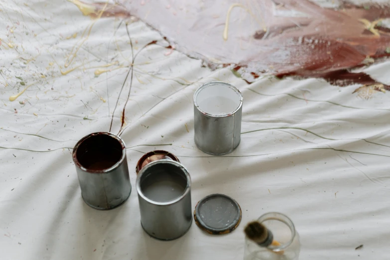 a couple of paint cans sitting on top of a table, inspired by Julian Schnabel, unsplash, action painting, brown, grey, blood stains, white