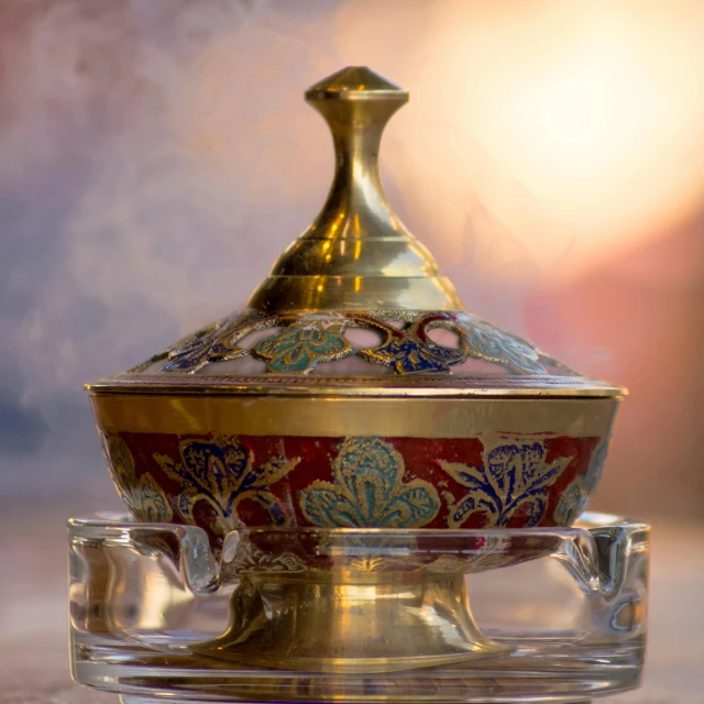 a glass bowl sitting on top of a table, by Adam Marczyński, pixabay contest winner, cloisonnism, incense, gold and red filigree, arab inspired, steamy