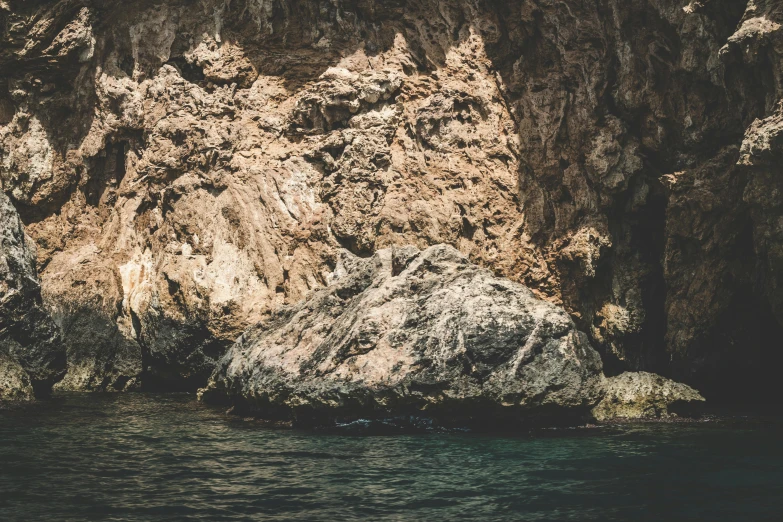 a man standing on top of a rock next to a body of water, inspired by Elsa Bleda, unsplash, romanticism, natural cave wall, 2 0 0 0's photo, mediterranean, ((rocks))