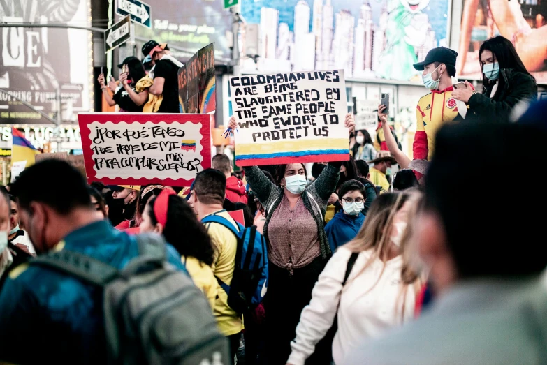 a crowd of people walking down a street holding signs, a picture, by Gina Pellón, pexels, red yellow blue, colombian, 2 0 2 2 photo, 🦩🪐🐞👩🏻🦳