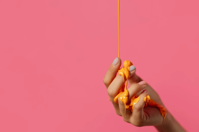 a close up of a person's hand holding a toy giraffe, a hyperrealistic painting, inspired by Lucio Fontana, trending on pexels, pink and orange, throwing spaghetti and meatballs, glossy yellow, studio shoot