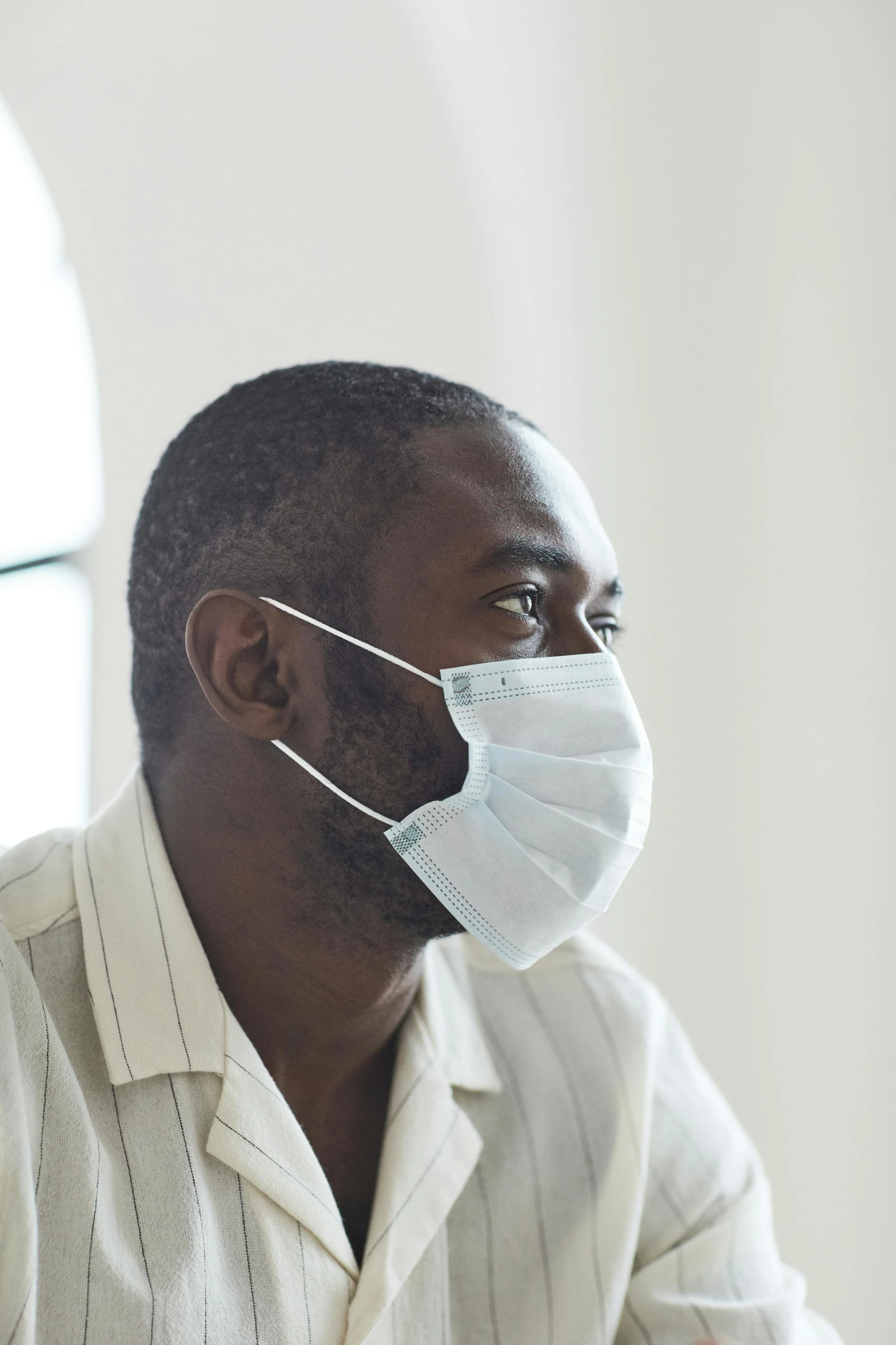 a man in a white shirt wearing a face mask, looking off into the distance, black man, hazy, (doctor)