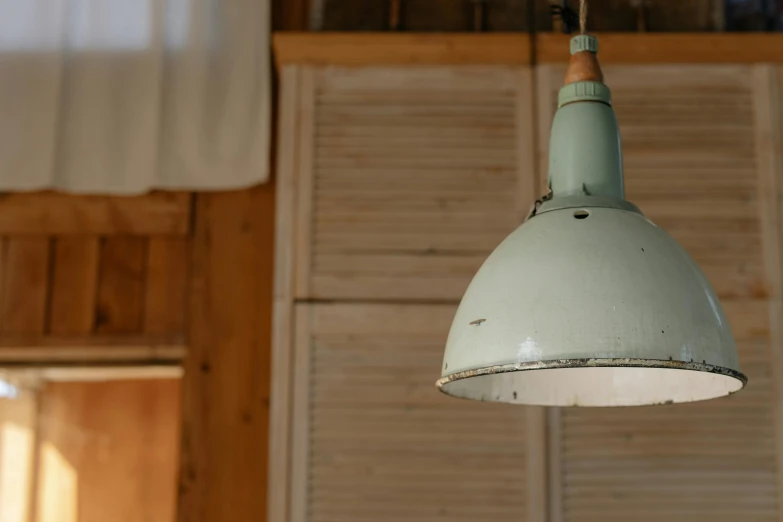 a light hanging from a ceiling in a room, by Niels Lergaard, unsplash, celadon glaze, dressed in a worn, a wooden, natural light outside