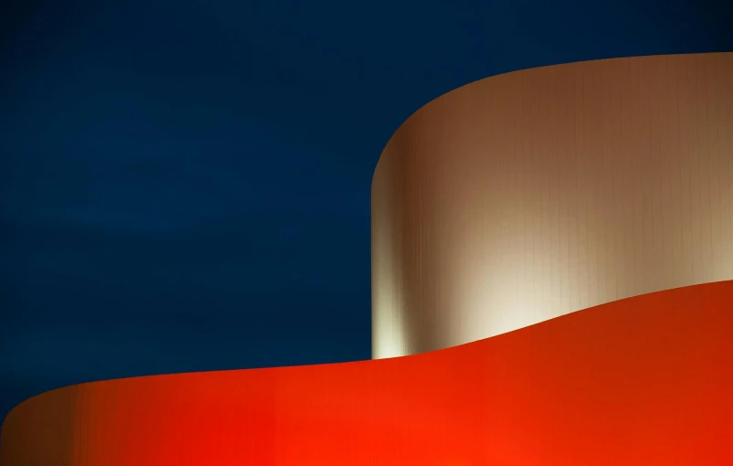 a red and white building with a blue sky in the background, an abstract sculpture, by Doug Ohlson, unsplash contest winner, (night), orange and blue tones, curved, industrial colours