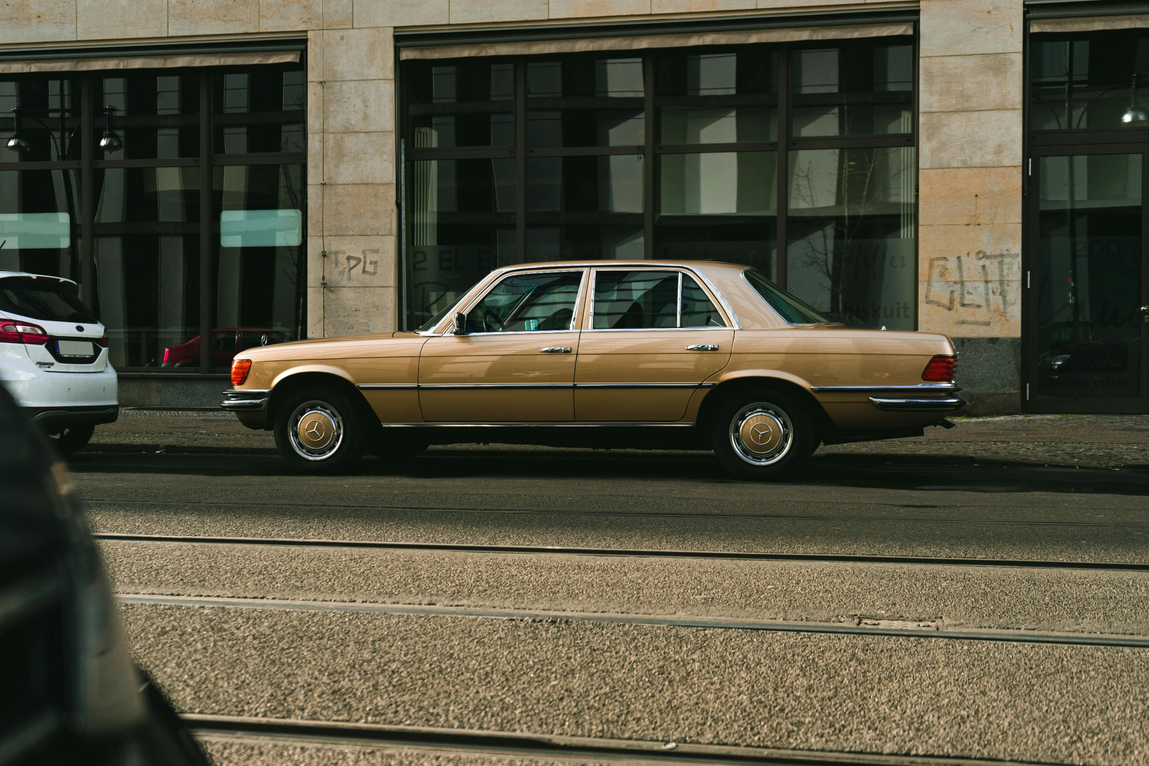 a car is parked on the side of the road, by Thomas Häfner, pexels contest winner, photorealism, beige and gold tones, berlin 1 9 8 2, mercedez benz, brown