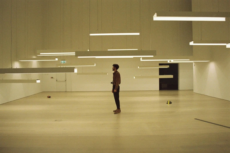 a man is standing in an empty room, inspired by Cerith Wyn Evans, unsplash, kinetic art, floating lights, hyperrealistic”, olafur eliasson, concert