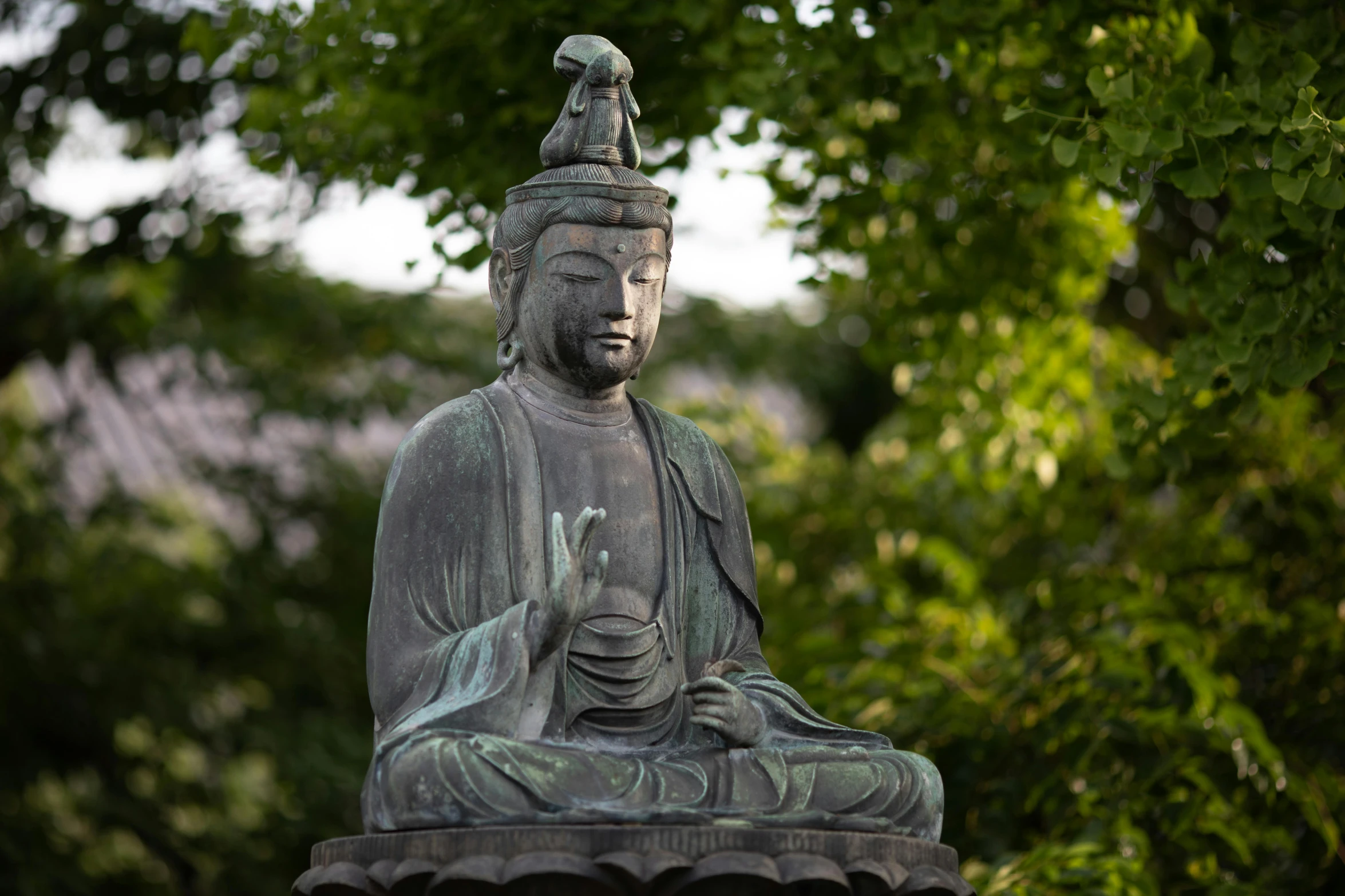 a statue with a bird sitting on top of it, inspired by Sesshū Tōyō, unsplash, sōsaku hanga, bronze statue, meditating in lotus position, looking towards camera, green blessing
