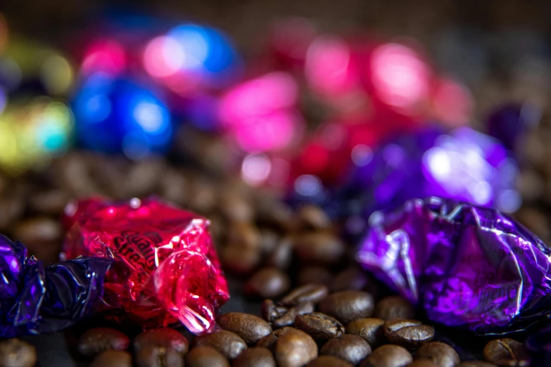 a pile of chocolates sitting on top of a pile of coffee beans, by Julia Pishtar, purple and pink and blue neons, purple and red, thumbnail, unblur