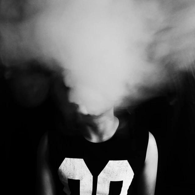a black and white photo of a person smoking a cigarette, unsplash, surrealism, head exploding, teenage boy, face obscured, in a cloud