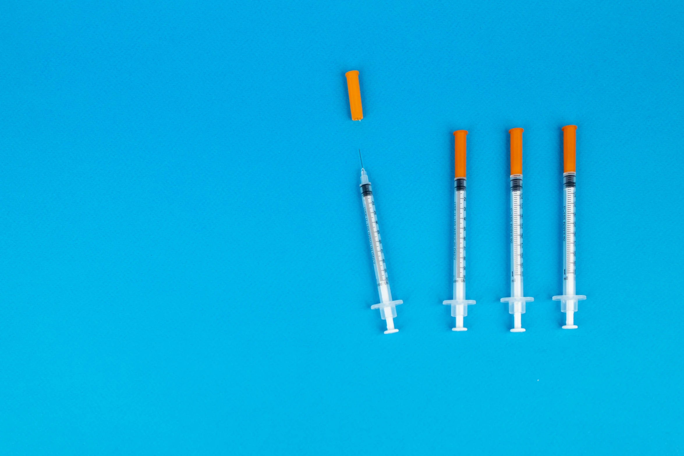 three syops sitting next to each other on a blue surface, shutterstock, syringes, blue!! with orange details, overdose, various sizes