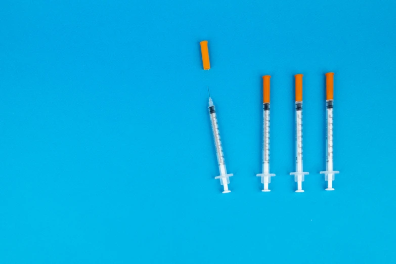 three syops sitting next to each other on a blue surface, shutterstock, syringes, blue!! with orange details, overdose, various sizes