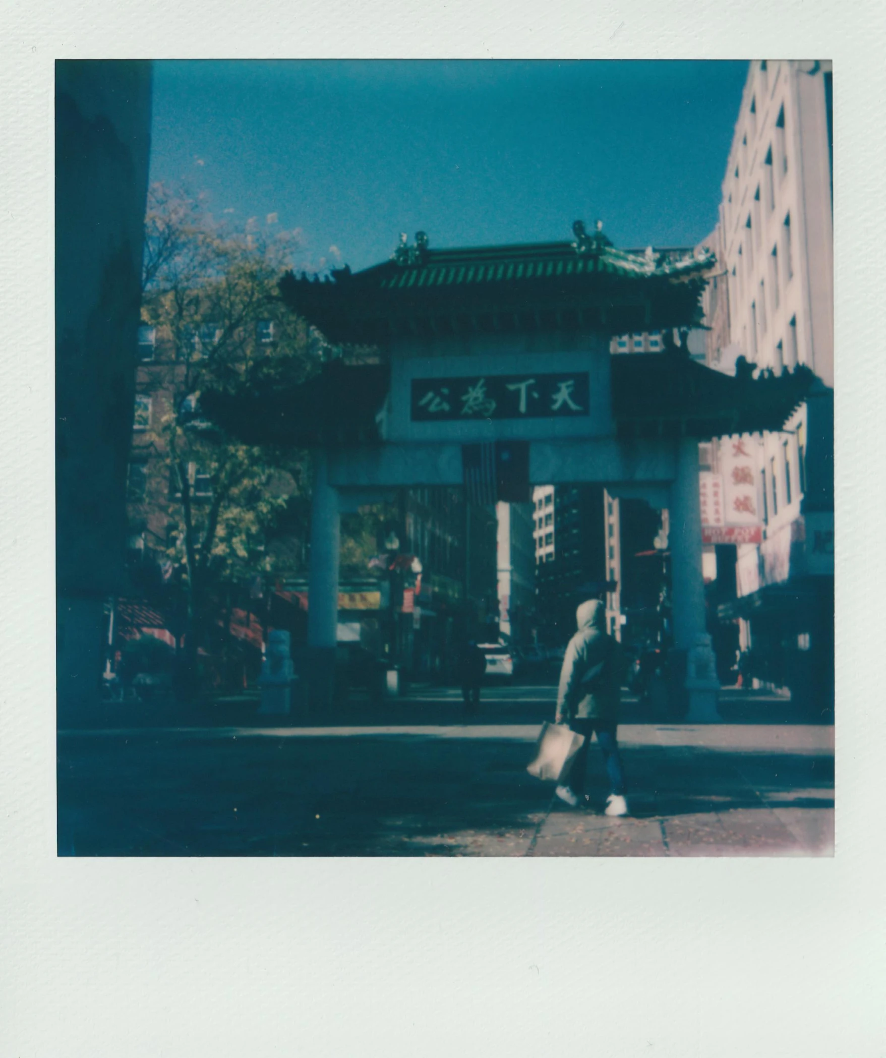 a man walking down a street past a tall building, a polaroid photo, with a chinese temple, basia tran, cyan, quaint