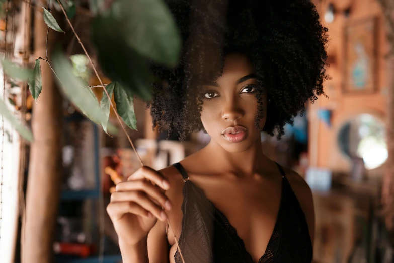 a close up of a person holding a flower, a photo, trending on pexels, afrofuturism, sexy girl with dark complexion, curls on top, beautiful surroundings, wearing a camisole