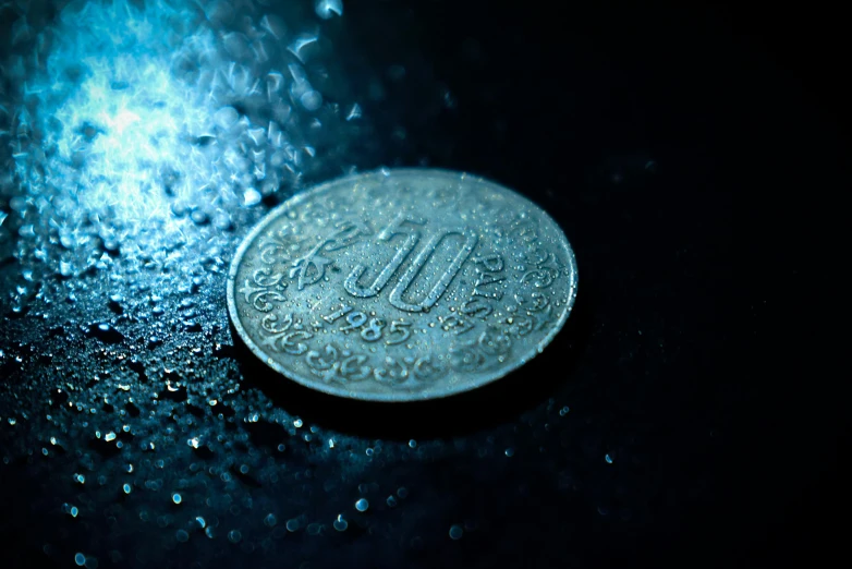 a close up of a coin on a wet surface, by Alejandro Obregón, pexels contest winner, extremely moody blue lighting, uttarakhand, retro effect, thumbnail