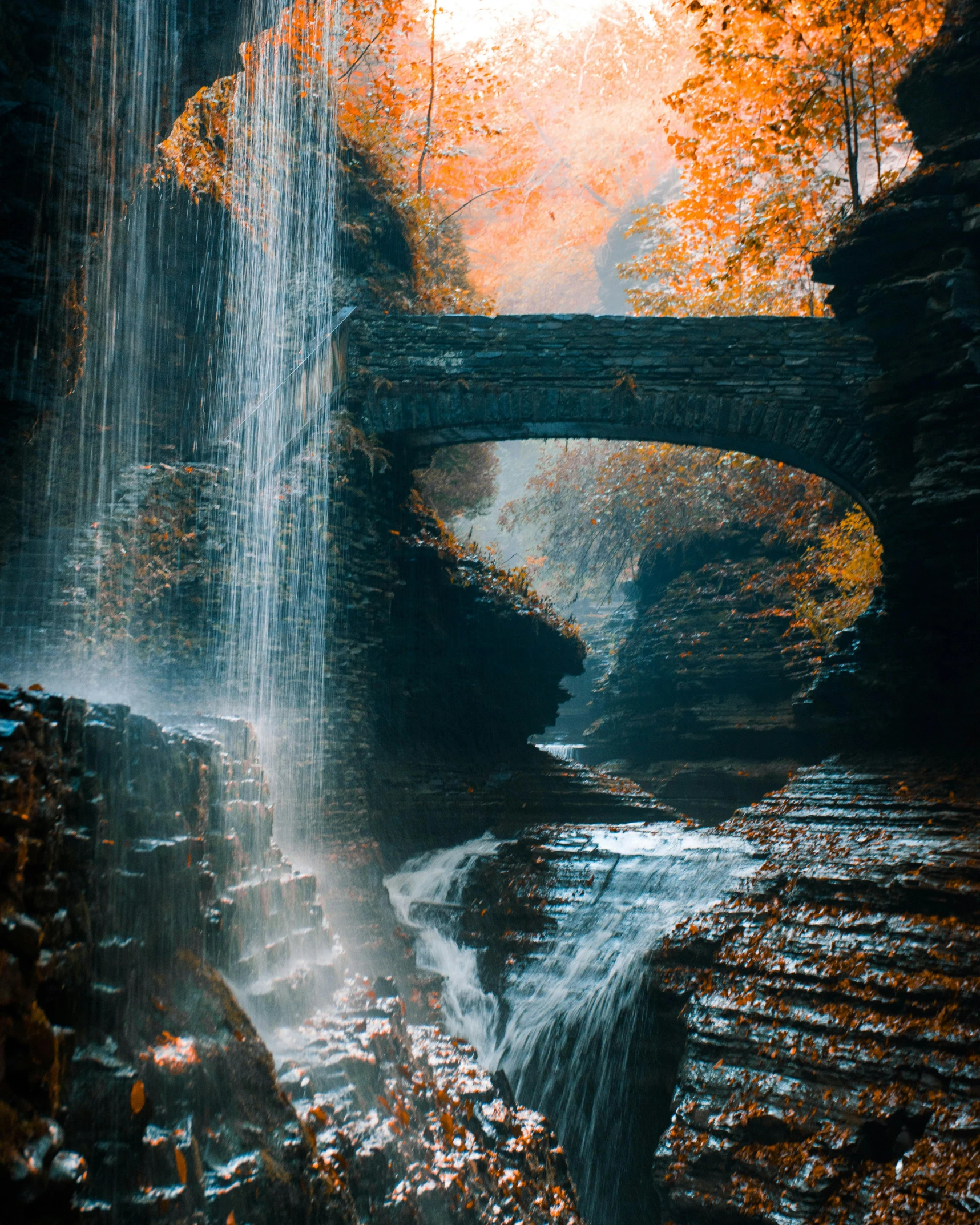 a waterfall with a bridge in the background, inspired by Elsa Bleda, pexels contest winner, hudson river school, renaissance autumnal, archs and walls, grotto, big island