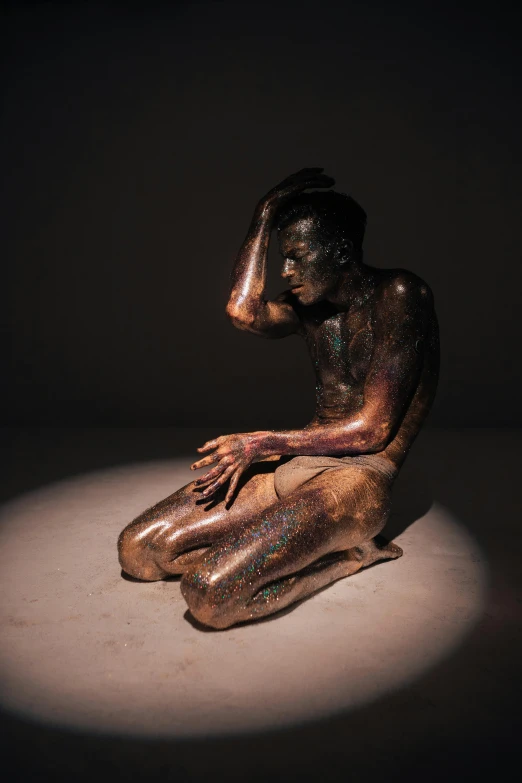 a bronze statue of a man sitting on the ground, unsplash, figurative art, iridescent skin, studio lit, worried, glittering skin