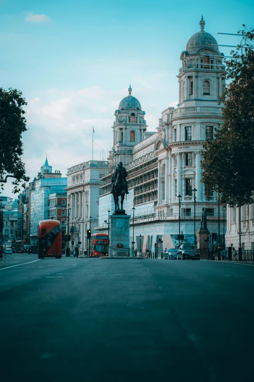 a double decker bus driving down a street next to tall buildings, a statue, pexels contest winner, neoclassicism, victorian buildings, kneeling, neoclassical tower with dome, united kingdom