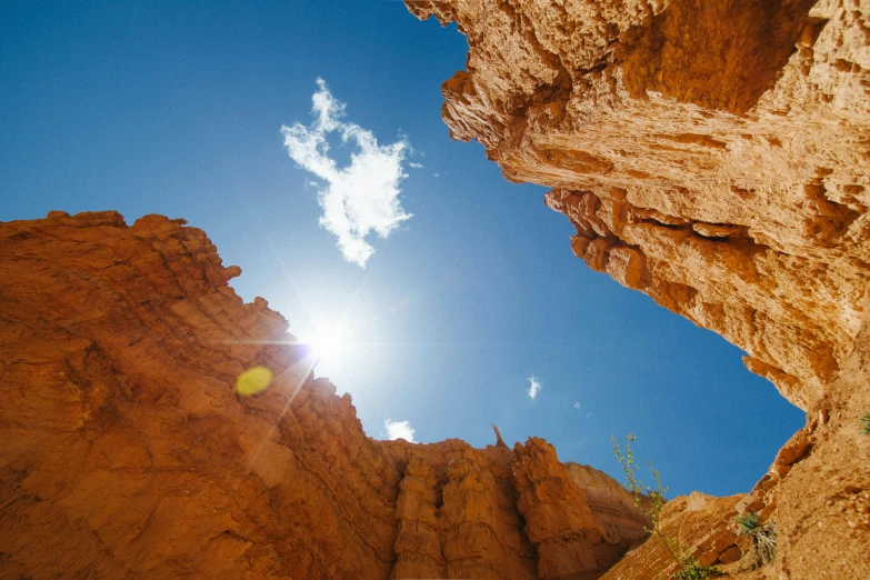 the sun shines through a hole in a canyon, unsplash contest winner, renaissance, archways between stalagtites, blue sky, australian outback, high quality product image”