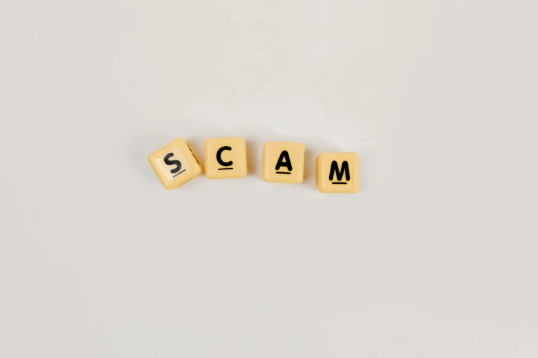 scrabbles spelling the word scam on a white background, by Sam Black, pexels, 🦩🪐🐞👩🏻🦳, gold, there was a noise, ad image