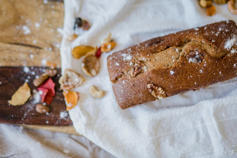 a loaf of bread sitting on top of a wooden cutting board, by Helen Stevenson, trending on pexels, gems and diamond for fruit, covered in white flour, cake in hand, caramel