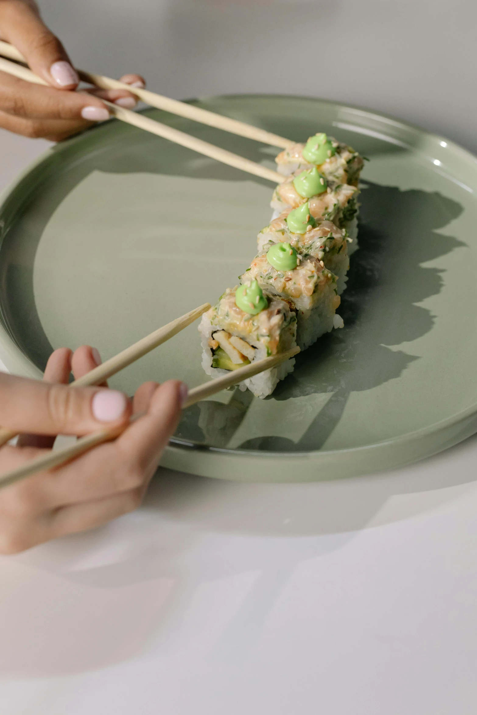 a person holding chopsticks over a plate with sushi on it, inspired by Maki Haku, pastel green, b - roll, 2 1 0 mm, lightening