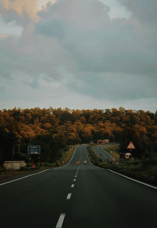 an empty road with trees in the background, yellow clouds, top of the hill, instagram picture, highways