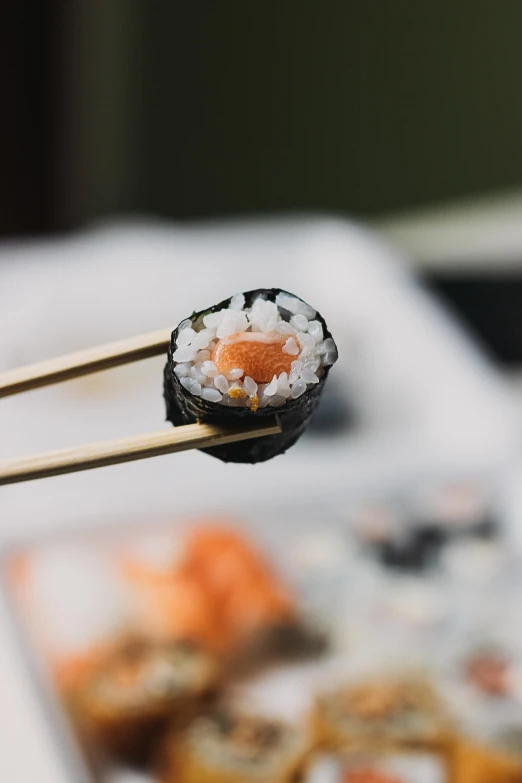 a pair of chopsticks holding a piece of sushi, unsplash, square, journalism photo, b - roll, spiky