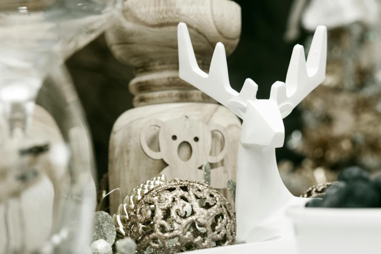 a white deer figurine sitting on top of a table, a marble sculpture, inspired by Ernest William Christmas, unsplash, variety of shapes and textures, white and silver, wooden decoration, zoomed in