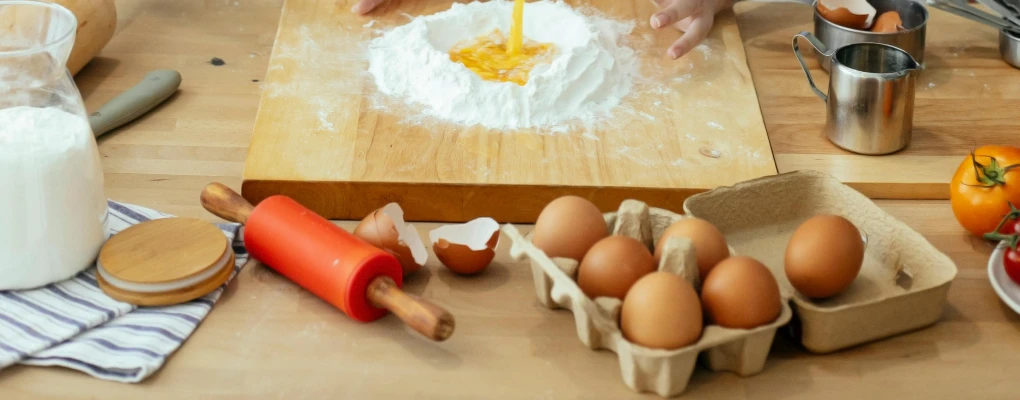 a wooden cutting board topped with eggs and flour, trending on pexels, process art, wooden art toys, pouring, chefs table, replicas