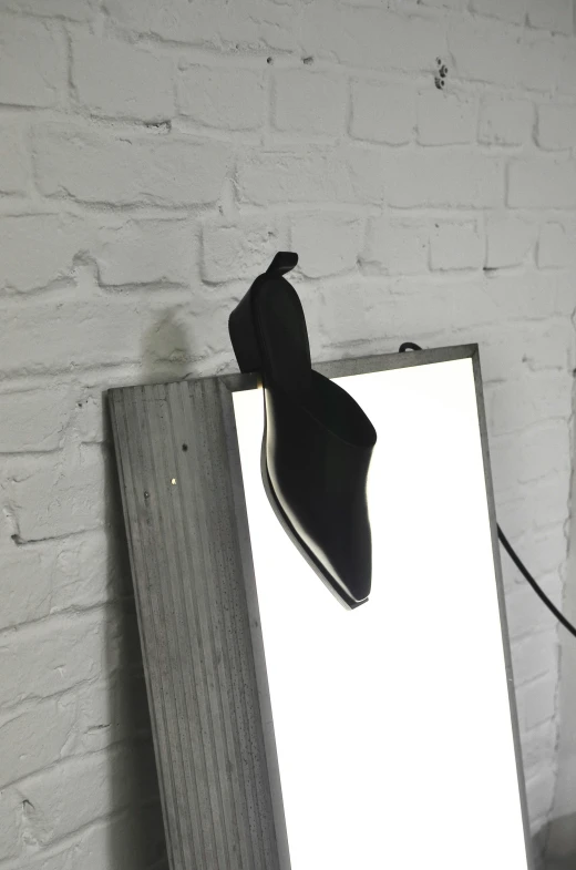 a mirror sitting in front of a white brick wall, pointy jester shoes, clamp shell lighting, on a mannequin. studio lighting, black edges