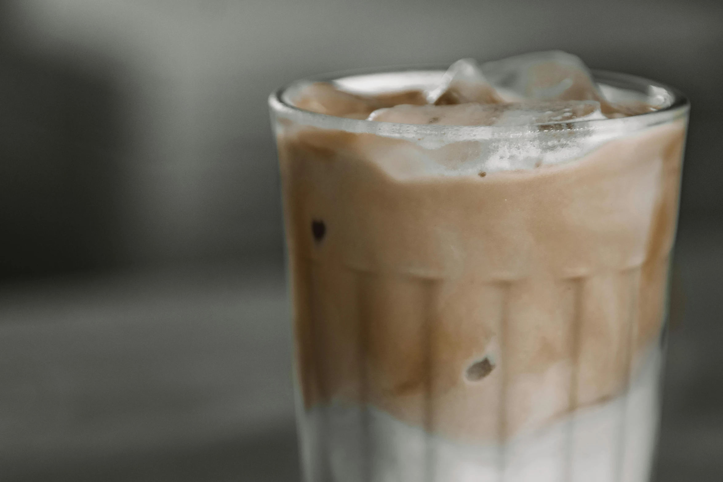 a glass of iced coffee sitting on top of a table, trending on unsplash, background image, soymilk, thumbnail, uncropped