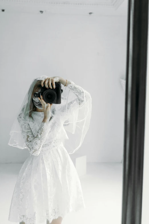 a woman taking a picture of herself in a mirror, inspired by Elsa Bleda, wearing a wedding dress, showstudio, full covered dress, holding a dslr camera