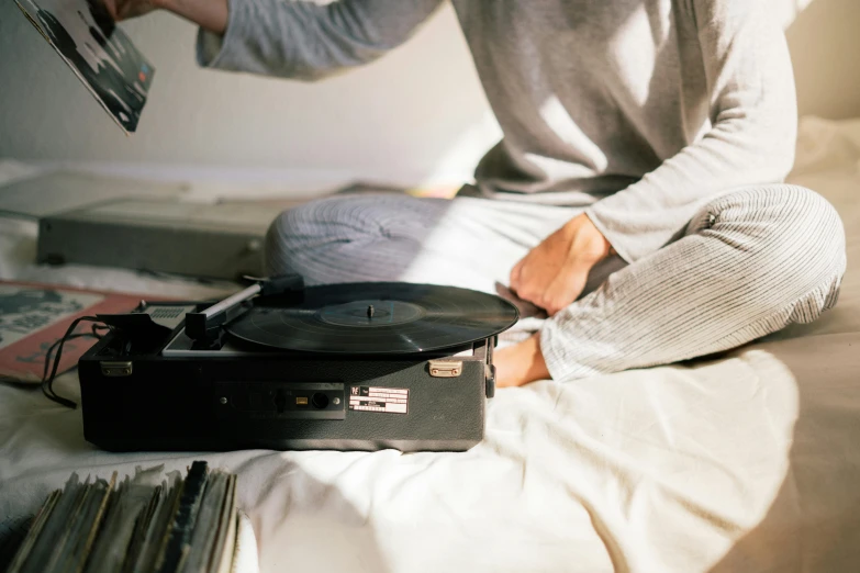 a man sitting on a bed next to a record player, trending on pexels, couple on bed, delicate details, simple aesthetic, laying down