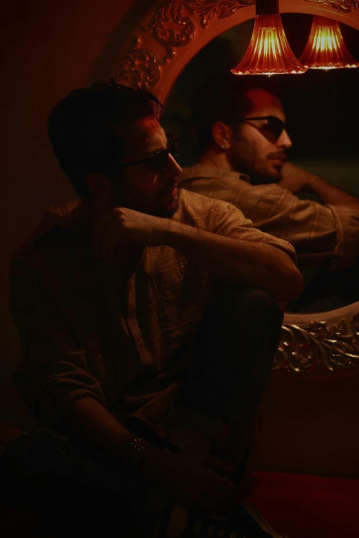 two men sitting on a couch in front of a mirror, inspired by Elsa Bleda, serial art, wearing red tainted glasses, profile shot, group of people in a dark room, promotional image