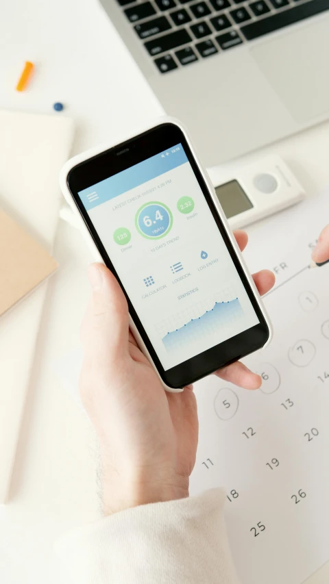 a person holding a smart phone in front of a laptop, by Robbie Trevino, pexels, white and pale blue toned, holding scale, app design, panoramic shot