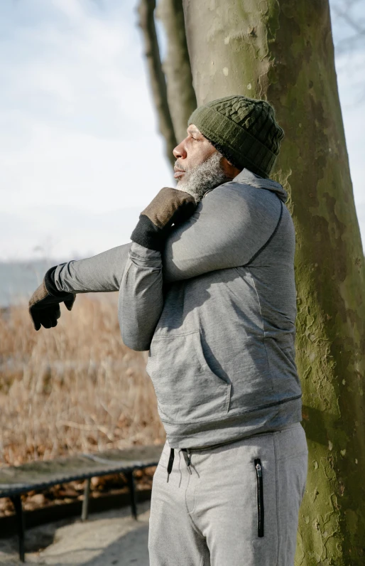 a man standing next to a tree in a park, by Jan Tengnagel, happening, dabbing, gray beard, cold winter, filmstill