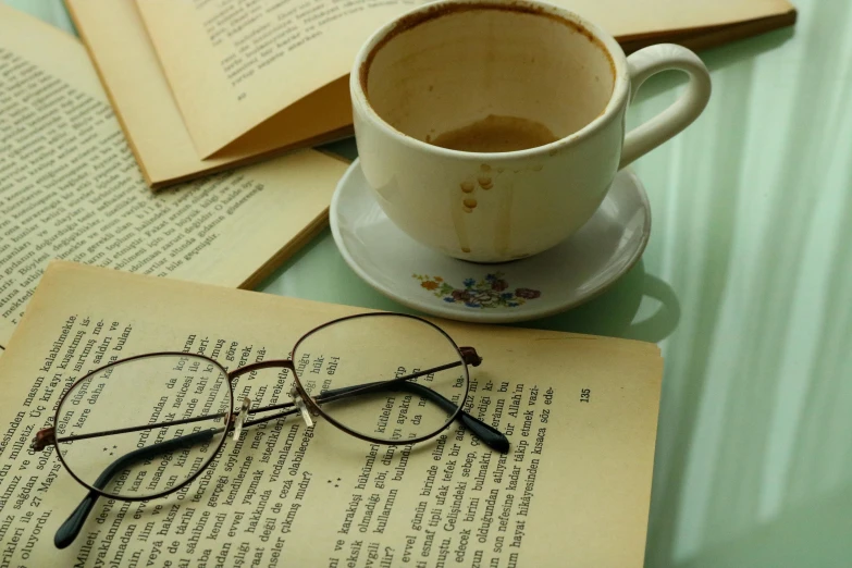 a cup of coffee sitting on top of an open book, a still life, by Lucia Peka, pixabay, square rimmed glasses, advert, aged 2 5, white
