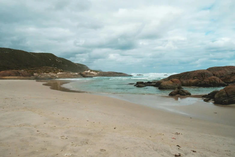 a sandy beach next to the ocean under a cloudy sky, a picture, unsplash, cape, ben nicholas, slide show, sparkling cove