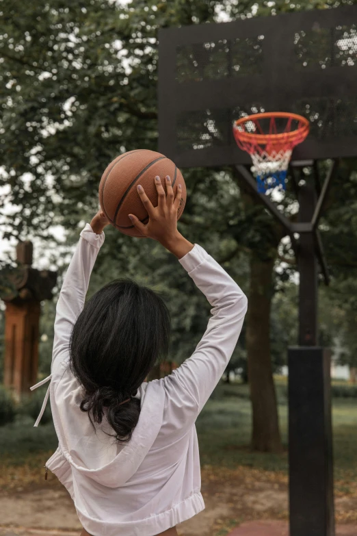 a woman standing on top of a basketball court holding a basketball, trending on dribble, in a park, pictured from the shoulders up, playing games, seen from the back
