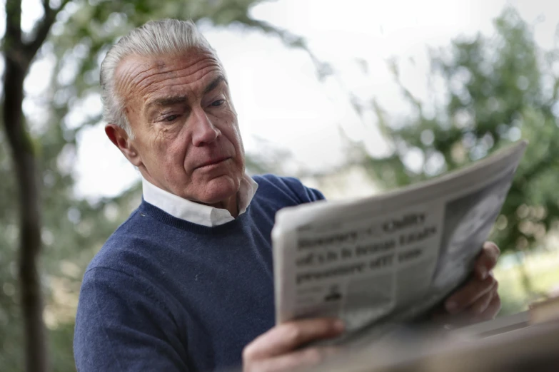 a man sitting at a table reading a newspaper, a silver haired mad, shot with sony alpha 1 camera, portrait image, calm weather