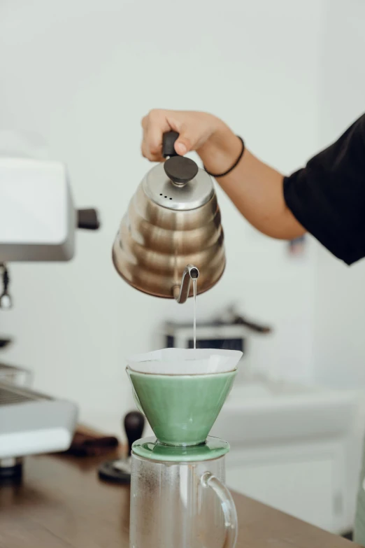 a close up of a person pouring something into a cup, a colorized photo, trending on unsplash, aussie baristas, stainless steal, green, cone shaped