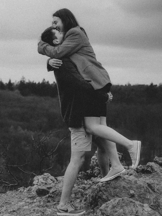 a black and white photo of two people hugging, a black and white photo, by Lucia Peka, standing on a hill, cinematic. by leng jun, famous photo, kiss