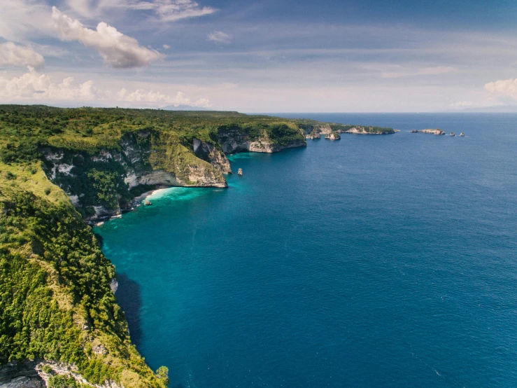 a large body of water next to a lush green hillside, a cartoon, pexels contest winner, sumatraism, ocean cliff view, blue ocean, conde nast traveler photo, concert