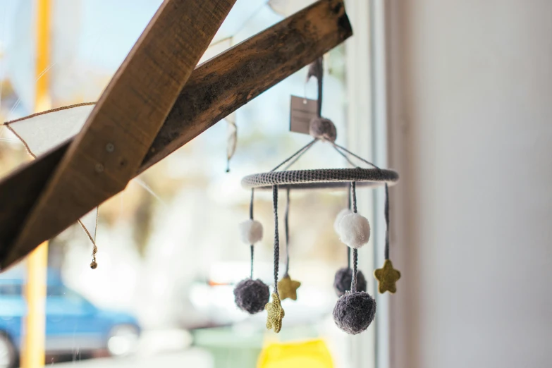 a baby mobile hanging from the side of a window, unsplash, product display photograph, stars on top of the crown, circular, grey