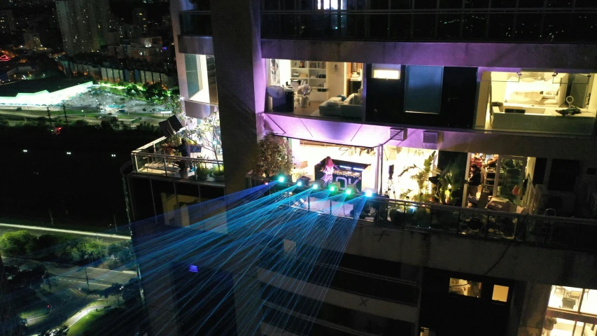 a view of a city at night from a high rise building, holography, lasers for lights, atrium, blue and purple lighting, des boutiques avec des neons