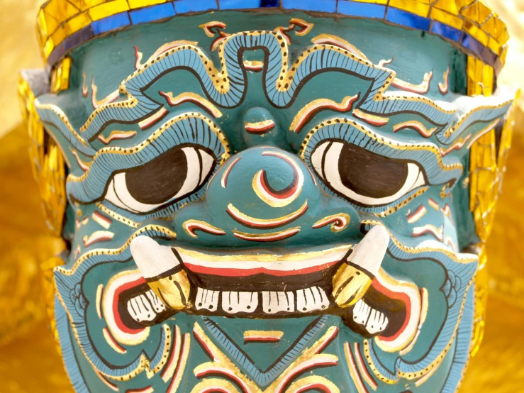 a close up of a mask on a table, a detailed painting, inspired by I Ketut Soki, pexels contest winner, cloisonnism, symmetrical face happy, ornate carved architecture, avatar image, narasimha