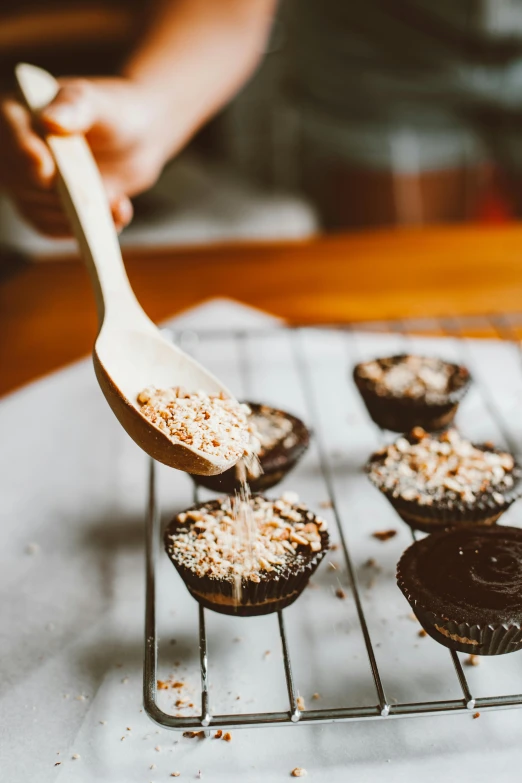 a person holding a wooden spoon over a tray of cupcakes, crackles, ferrofluid, coconuts, thumbnail