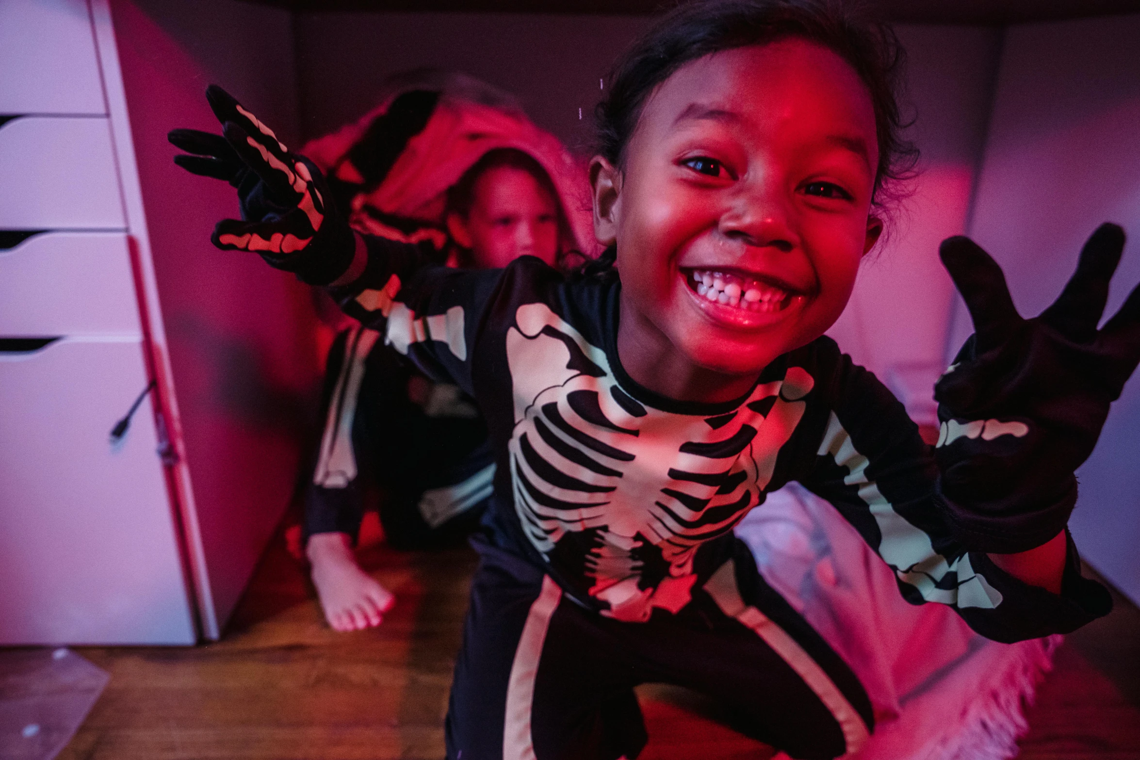 a couple of kids that are standing in a room, spooky halloween fun, lit from below, smiling down from above, studio bones